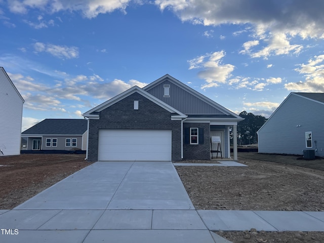 view of front of property with a garage, central AC unit, concrete driveway, board and batten siding, and brick siding