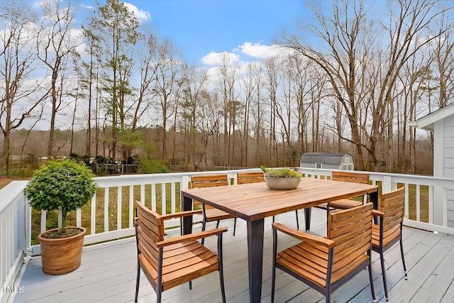 wooden terrace with an outdoor structure, outdoor dining area, and a shed