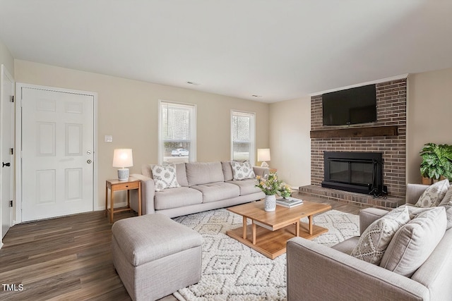 living room featuring a brick fireplace and wood finished floors