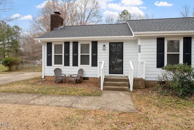 view of front of home featuring entry steps, fence, a shingled roof, crawl space, and a chimney