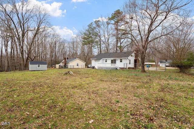 view of yard with an outbuilding, a wooden deck, a storage shed, and a fenced backyard