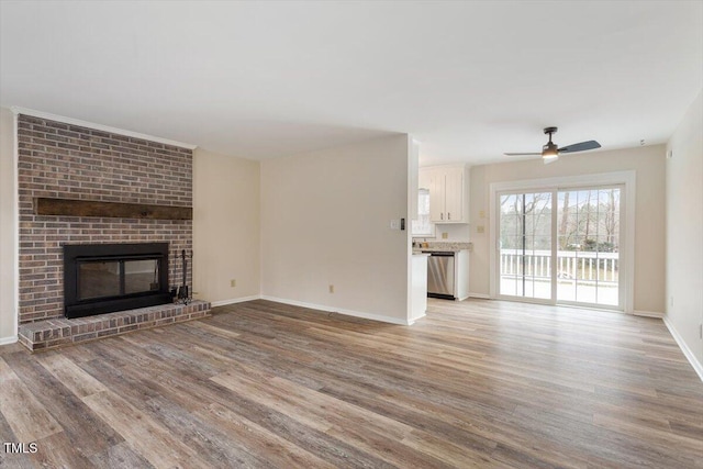 unfurnished living room featuring baseboards, a ceiling fan, light wood-style flooring, and a fireplace