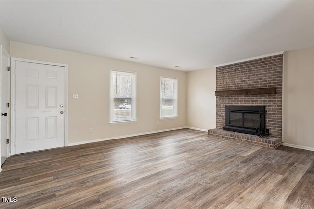 unfurnished living room featuring visible vents, a fireplace, baseboards, and wood finished floors