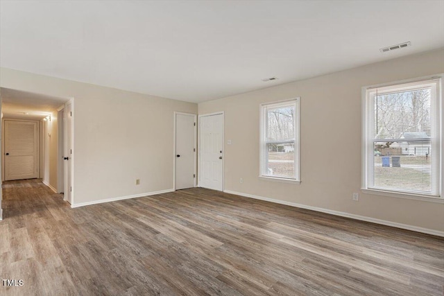 unfurnished room with visible vents, wood finished floors, and baseboards