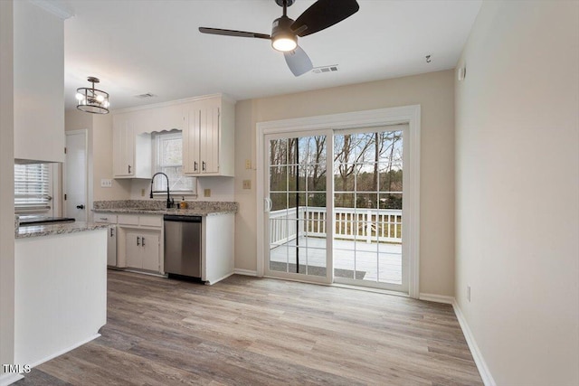 kitchen featuring stainless steel dishwasher, white cabinets, light wood-style floors, and visible vents