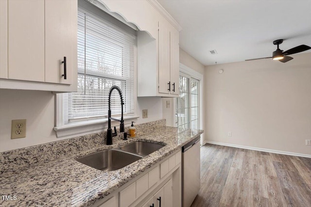 kitchen with a sink, stainless steel dishwasher, white cabinetry, light wood finished floors, and baseboards