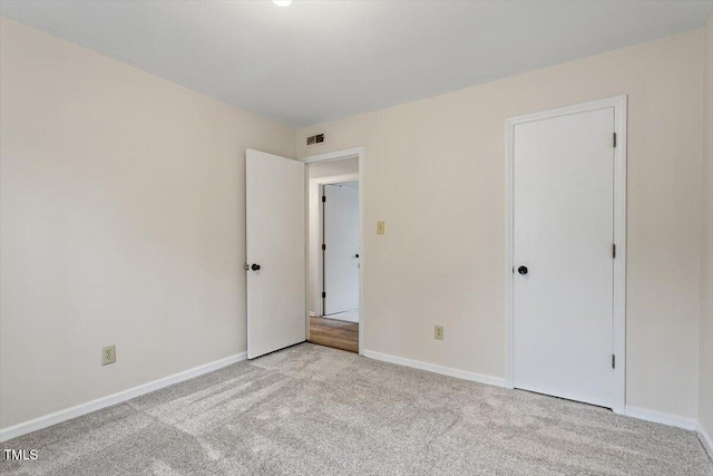 unfurnished bedroom with visible vents, light colored carpet, and baseboards