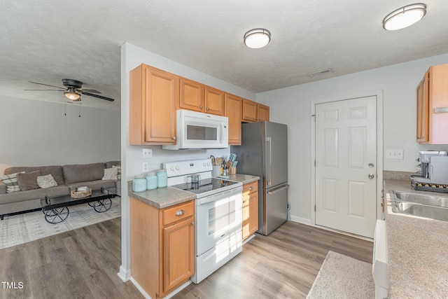 kitchen with white appliances, visible vents, open floor plan, and light wood-style floors