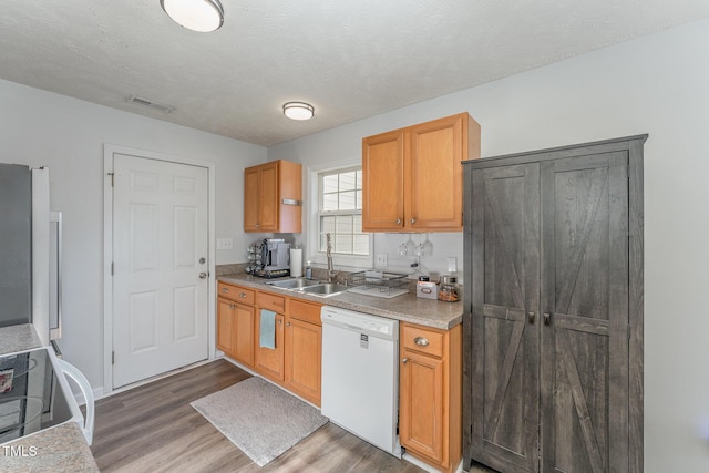 kitchen with visible vents, electric range oven, wood finished floors, white dishwasher, and a sink