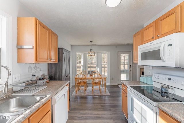 kitchen with white appliances, dark wood-style flooring, a textured ceiling, pendant lighting, and a sink