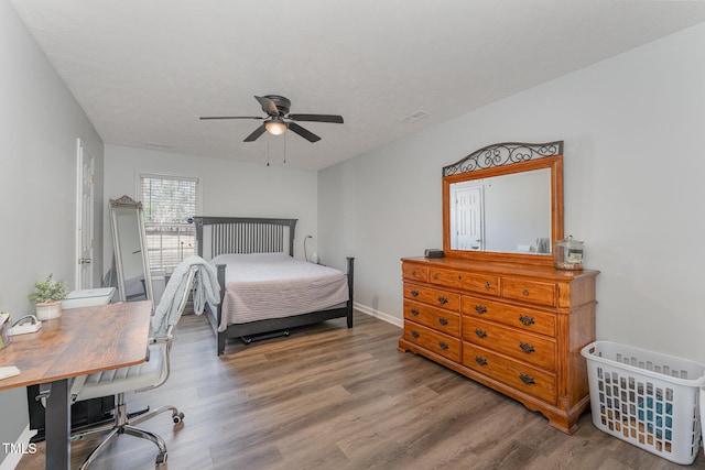 bedroom with ceiling fan, wood finished floors, visible vents, and baseboards