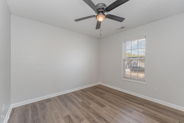 spare room with a ceiling fan, wood finished floors, visible vents, and baseboards