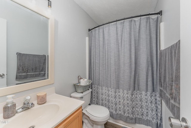 full bathroom featuring toilet, curtained shower, a textured ceiling, and vanity