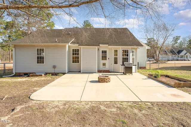 back of property with roof with shingles, fence, a fire pit, and a patio