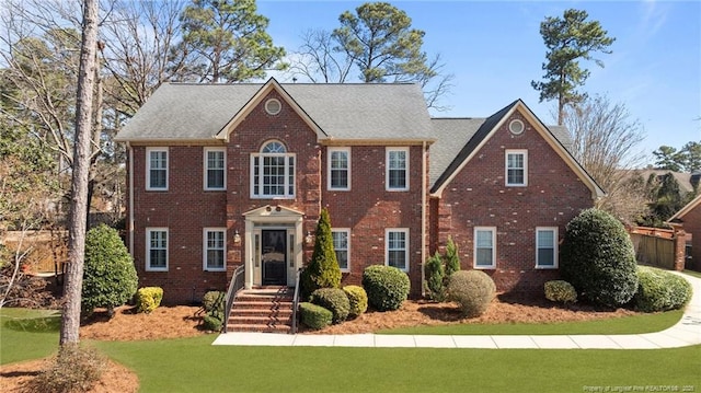 colonial home with brick siding and a front yard