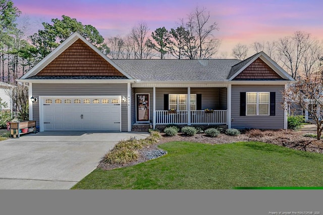 view of front facade with a porch, a garage, concrete driveway, a yard, and roof with shingles