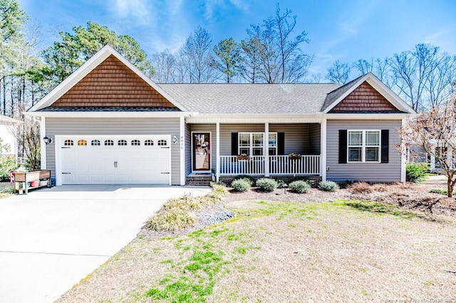 view of front of property with covered porch, driveway, a shingled roof, and a garage