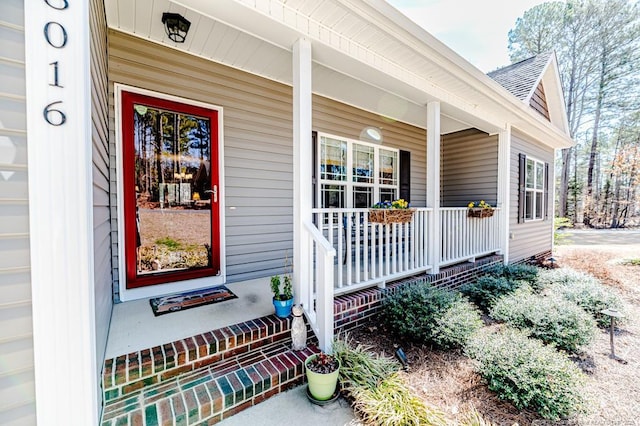 property entrance with a garage, covered porch, and a shingled roof