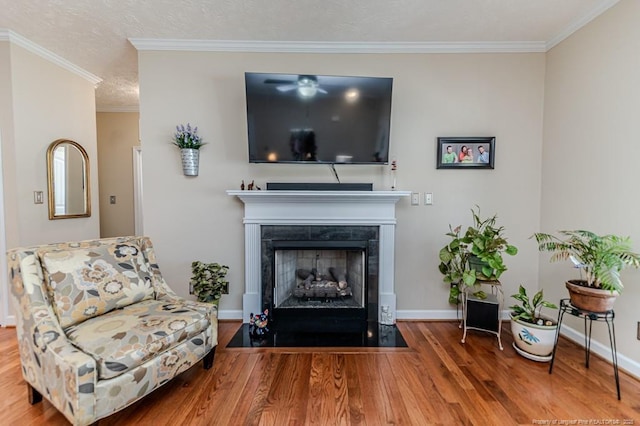 living area with baseboards, crown molding, a tiled fireplace, and wood finished floors