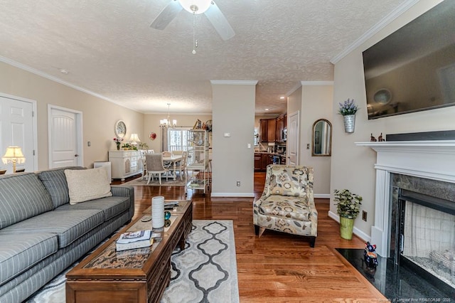 living room with a textured ceiling, a premium fireplace, wood finished floors, baseboards, and ornamental molding