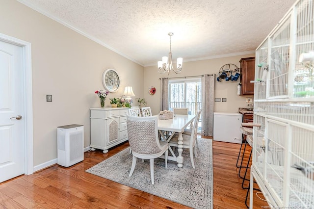 dining space with a textured ceiling, a notable chandelier, baseboards, light wood-style floors, and ornamental molding