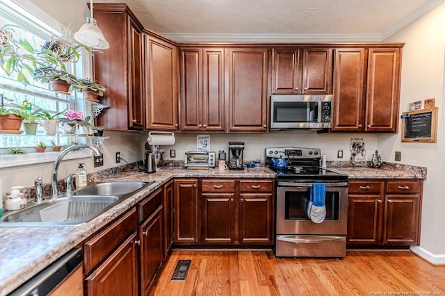 kitchen featuring light wood finished floors, visible vents, appliances with stainless steel finishes, a textured ceiling, and a sink