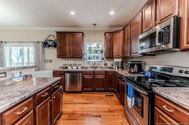 kitchen with light wood-style flooring, appliances with stainless steel finishes, ornamental molding, a sink, and light stone countertops