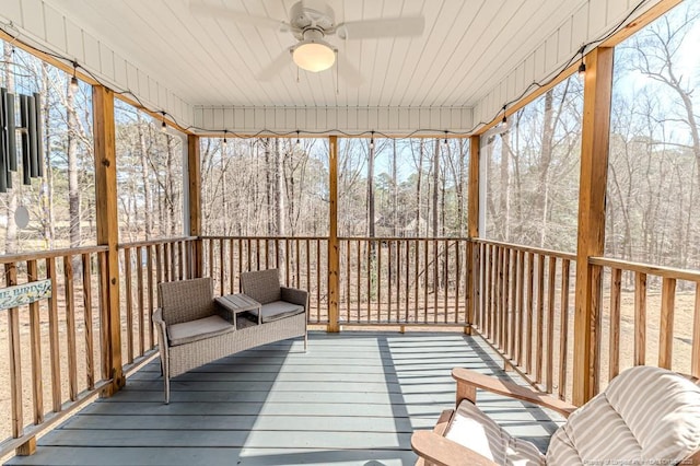 wooden deck with ceiling fan and a wooded view