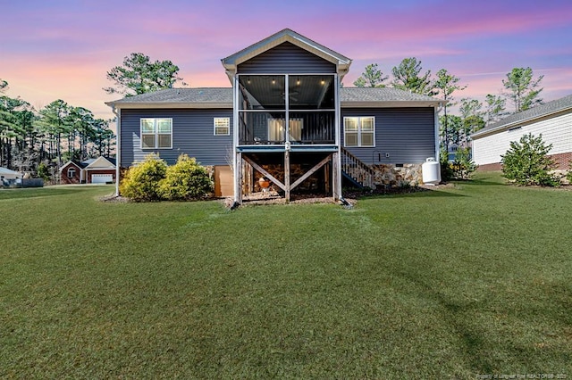 back of house at dusk featuring a sunroom, a yard, stairway, and crawl space