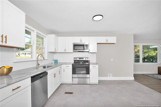 kitchen featuring stainless steel appliances, a sink, and white cabinets