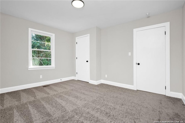 empty room with carpet floors, visible vents, and baseboards