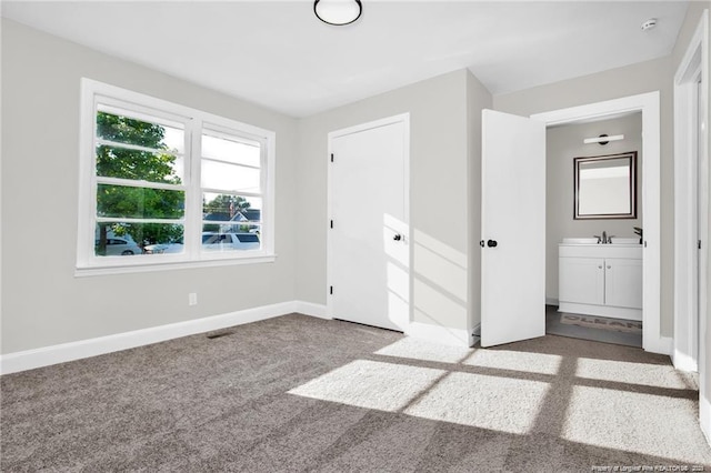 unfurnished bedroom with a closet, visible vents, ensuite bathroom, carpet flooring, and baseboards