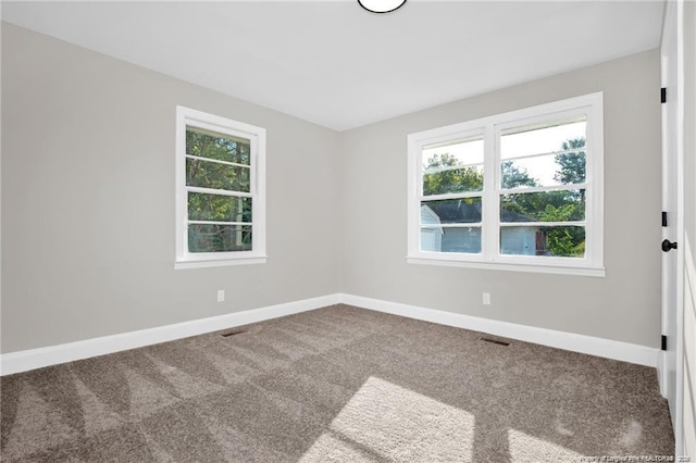 spare room featuring a healthy amount of sunlight, carpet flooring, and baseboards