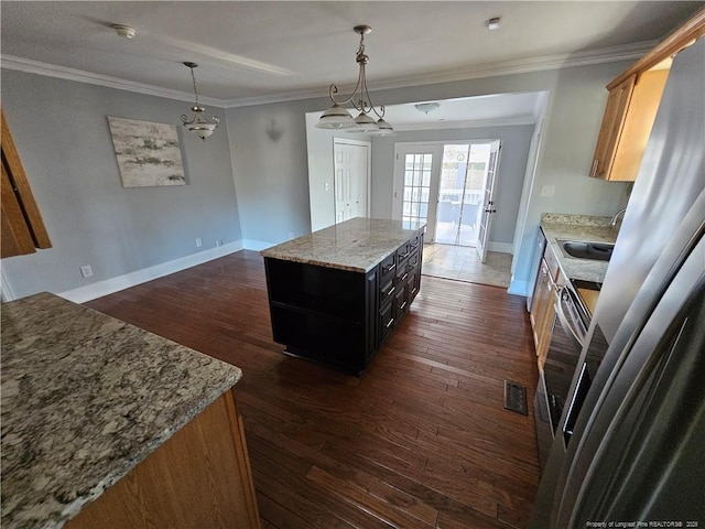 kitchen with baseboards, dark wood finished floors, a center island, crown molding, and a sink