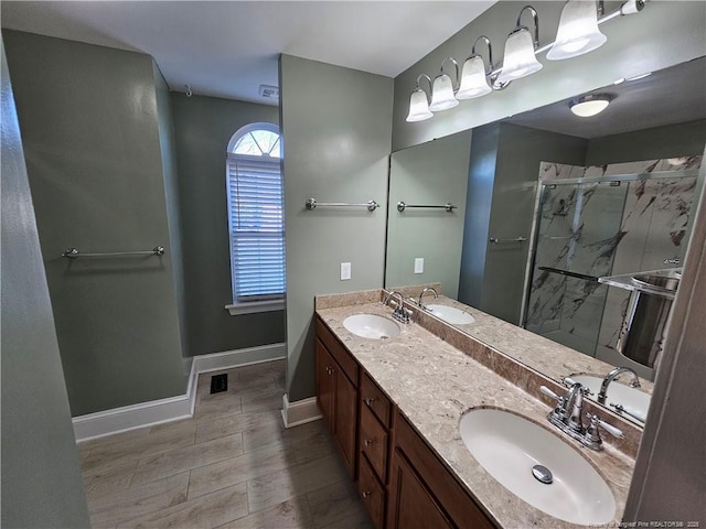 bathroom featuring baseboards, a sink, and a marble finish shower