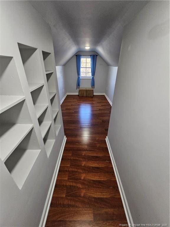 bonus room featuring built in features, baseboards, wood finished floors, vaulted ceiling, and a textured ceiling