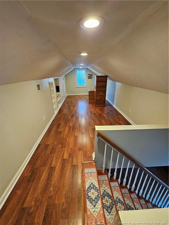 additional living space with built in shelves, lofted ceiling, baseboards, and wood finished floors