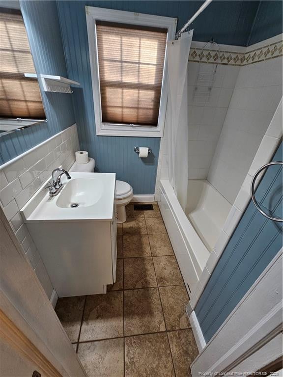 bathroom with toilet, a wainscoted wall, shower / bath combination with curtain, and vanity