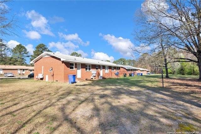 rear view of property featuring crawl space, brick siding, and a yard