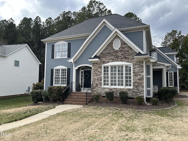 view of front of home featuring crawl space, stone siding, a shingled roof, and a front yard