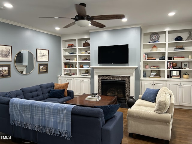 living room featuring ceiling fan, dark wood-type flooring, a premium fireplace, built in features, and crown molding