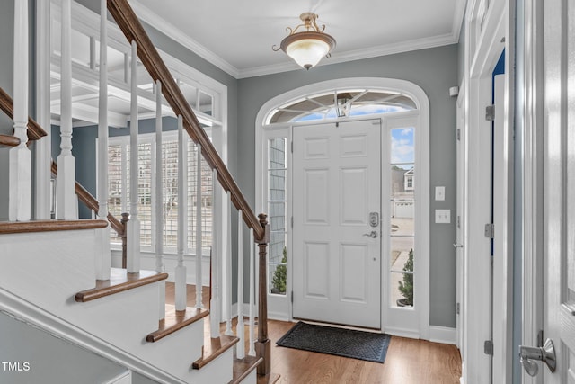 foyer with stairway, wood finished floors, baseboards, and ornamental molding