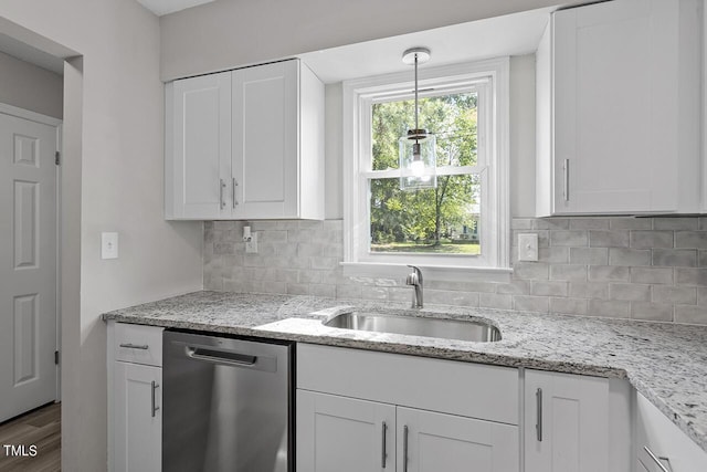 kitchen featuring wood finished floors, a sink, white cabinetry, stainless steel dishwasher, and tasteful backsplash