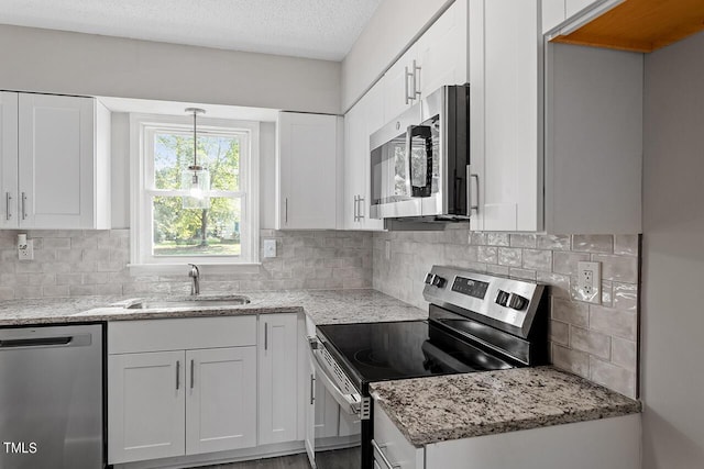 kitchen with stainless steel appliances, white cabinetry, a sink, and light stone counters