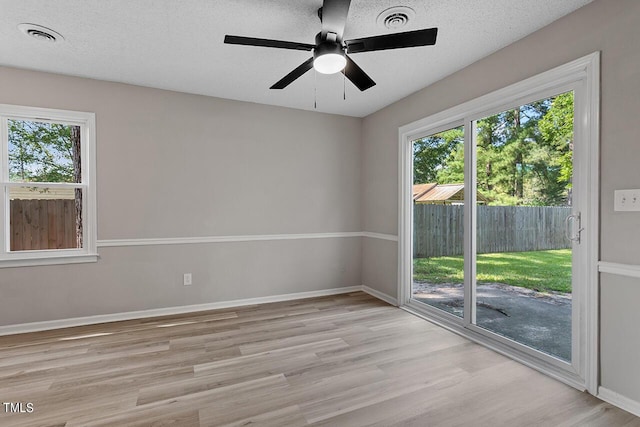 unfurnished room with light wood-type flooring, visible vents, and a textured ceiling