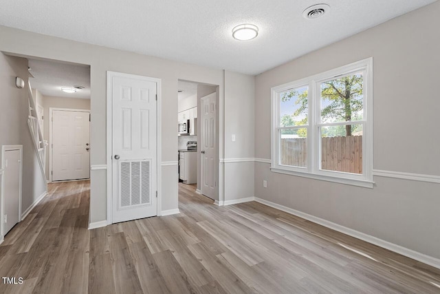 unfurnished room featuring baseboards, visible vents, and light wood-style floors