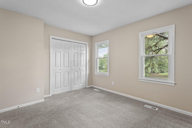 unfurnished bedroom featuring baseboards, visible vents, a textured ceiling, and carpet flooring