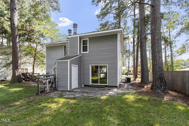 rear view of property with cooling unit, a lawn, and fence