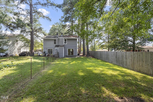 rear view of property with a fenced backyard and a lawn