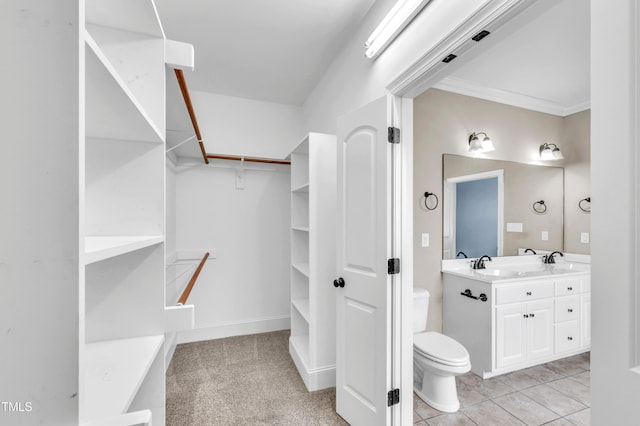 bathroom with a sink, double vanity, toilet, and ornamental molding